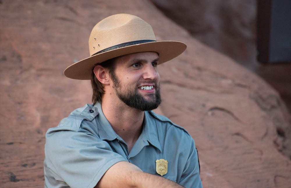 Martin Tow wears a broad brim hat and NPS uniform with shield-shaped badge bearing a bison pinned to his shirt.